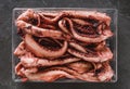 Fresh raw tentacles of octopus on box over dark stone background. Seafood, top view, flat lay, copy space Royalty Free Stock Photo