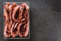Fresh raw tentacles of octopus on box over dark stone background. Seafood, top view, flat lay, copy space Royalty Free Stock Photo