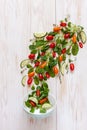 Fresh raw tomatoes, cucumbers, baby spinach and seasonal greens. Top view, close-up on white wooden background Royalty Free Stock Photo