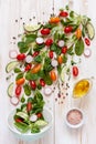 Fresh raw tomatoes, cucumbers, baby spinach and seasonal greens. Top view, close-up on white wooden background Royalty Free Stock Photo