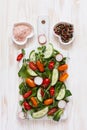 Fresh raw tomatoes, cucumbers, baby spinach and seasonal greens. Top view, close-up on white wooden background Royalty Free Stock Photo