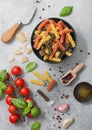 Fresh raw tricolore fusilli pasta in black bowl with cherry tomatoes and basil, garlic and oil with parmesan cheese on light Royalty Free Stock Photo
