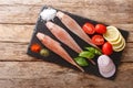 Fresh raw Triglidae fish with spices, tomatoes, onions and lemon close-up on a slate board. Horizontal top view Royalty Free Stock Photo