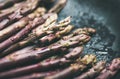 Fresh raw uncooked purple asparagus over dark background, horizontal composition