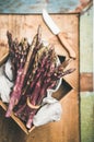 Fresh raw uncooked purple asparagus over rustic background, selective focus