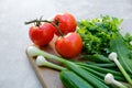 Fresh raw vegetables on wooden cutting board. Close-up view salad ingredients: tomatoes, green onion, parsley, cucumbers. Healthy Royalty Free Stock Photo