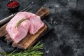 Fresh Raw whole big turkey breast fillet on wooden board. Black background. Top View. Copy space