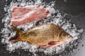 Fresh raw whole mirror carp and fish fillet with spices, lemon on ice over dark stone background. Creative layout made of fish