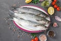 Fresh ready to cook raw mullets with ingredients and seasonings like parsley, lemon, cherry tomatoes, red onion and