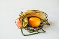 Fresh real fruits without retouching in mesh string bag on white background, reasonable reusable use of things,well-being