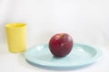 Fresh red apple on blue plate. Royalty Free Stock Photo