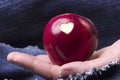 Fresh red apple with a heart shaped cut-out in woman hand on den Royalty Free Stock Photo