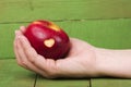 Fresh red apple with a heart shaped cut-out in woman hand on woo Royalty Free Stock Photo