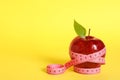 Fresh red apple with measuring tape on yellow background. Space for text Royalty Free Stock Photo