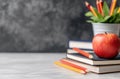 Fresh red apple sits on stacked notebooks in a classroom with colorful pencils in background Royalty Free Stock Photo