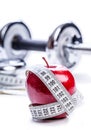 Fresh red apple, tape measure, and in the background Fitness dumbbells. Royalty Free Stock Photo