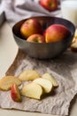 Fresh red apples in a stylish iron dish lying on a white window sill. Apple slices and a glass of milk are used as
