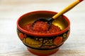 Fresh red caviar in wooden painted traditional style Khokhloma bowl with spoon on rustic table