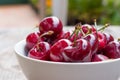 Fresh red cherries in a bowl, outdoors on a garden table