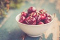 Fresh red cherries in a bowl, outdoors on a garden table