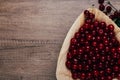 Fresh red cherries in a wooden plate on a wooden table. wooden plate on a wooden background.next to it is a cherry branch with che Royalty Free Stock Photo