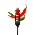 Fresh red cherry tomato and hot chili pepper on black fork isolated on white Royalty Free Stock Photo