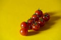 Fresh red cherry tomatoes with green stems isolated on yellow background Royalty Free Stock Photo