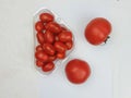 Cherry tomatoes in plastic container and whole tomatoes on white background Royalty Free Stock Photo