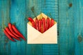 Fresh red chili pepper in a blue envelope on wooden background