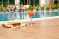 Fresh red cocktail with ice in glass, beach hat and sunglasses on swimming pool. Tropical juice on luxury vacations Royalty Free Stock Photo
