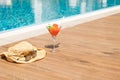 Fresh red cocktail with ice in glass, beach hat and sunglasses on swimming pool. Tropical juice on luxury vacations Royalty Free Stock Photo