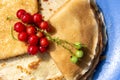 Fresh red currant berries and a stack of pancakes lie on a large blue plate top view. close-up Royalty Free Stock Photo