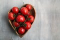 Fresh red delicious tomatoes in the heart shape wooden plate on