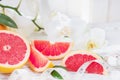 Fresh red grapefruit and grapefruit slices and measuring tape, on rustic white wooden table opposite the blinds.