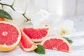 Fresh red grapefruit and grapefruit slices on white wooden table opposite the blinds. Healthy food, diet concept