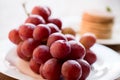 Fresh red grapes on plate, pancakes behind Royalty Free Stock Photo