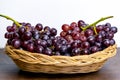 Fresh red grapes without seeds in a wooden basket placed on a table and a white background Royalty Free Stock Photo