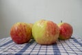 Fresh red-green apples, with water drops on surface of peel, lying picturesquely on white waffle fabric textile tablecloth. Royalty Free Stock Photo