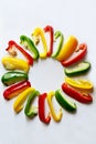Fresh red, green and yellow bell peppers capsicum has been cut into pieces arranged in a circle isolated on white background. Co Royalty Free Stock Photo