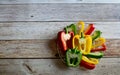 Fresh red, green and yellow bell peppers capsicum has been cut into pieces in clear glass dish on the wooden floor background. Royalty Free Stock Photo