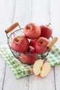 Fresh red juicy apples in a basket on a green textile on a wooden background Royalty Free Stock Photo