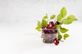 Fresh red juicy cherries with green leaves and tails in transparent plastic box in soft light white interior of kitchen. Royalty Free Stock Photo