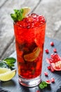 Fresh red lemonade with mint, pomegranate, lime and ice in glass on wooden background. Summer drinks and cocktails Royalty Free Stock Photo