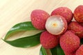 Fresh red lychee and peeled with leaves on wooden background with copy space