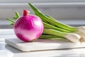 Fresh red onion and spring onions lying on white cutting board Royalty Free Stock Photo