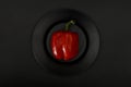 Fresh red paprika peppers in a black plate on a black background, close-up top view. Royalty Free Stock Photo