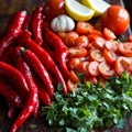 Fresh red peppers, tomatoes, garlic, lemon, and cilantro on rustic table Royalty Free Stock Photo