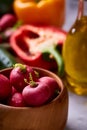 Fresh red radish in wooden bowl among plates with vegetables, herbs and spicies, top view, selective focus. Royalty Free Stock Photo