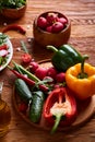 Fresh red radish in wooden bowl among plates with vegetables, herbs and spicies, top view, selective focus. Royalty Free Stock Photo