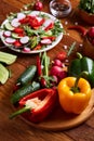 Fresh red radish in wooden bowl among plates with vegetables, herbs and spicies, top view, selective focus. Royalty Free Stock Photo